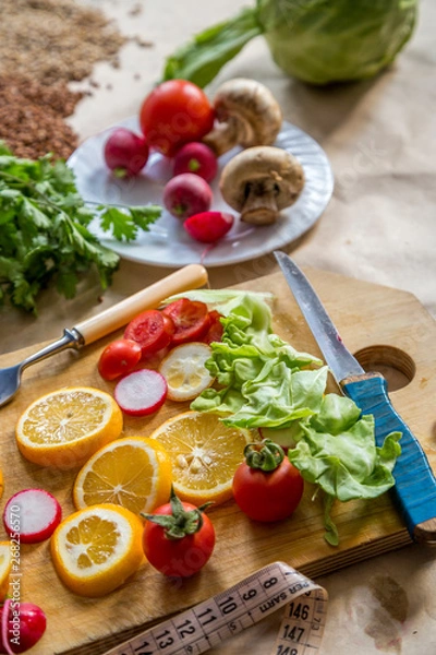 Fototapeta Healthy vegan food background with cutting board and lemon slices. Top view to organic food background with cutting board and lemon slices