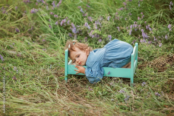 Fototapeta Portrait of little girl lying in small bed outside in summertime