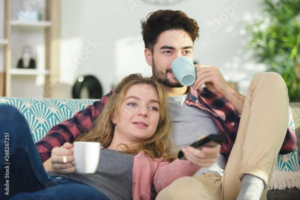 Obraz picture of couple drinking warm beverage on the sofa