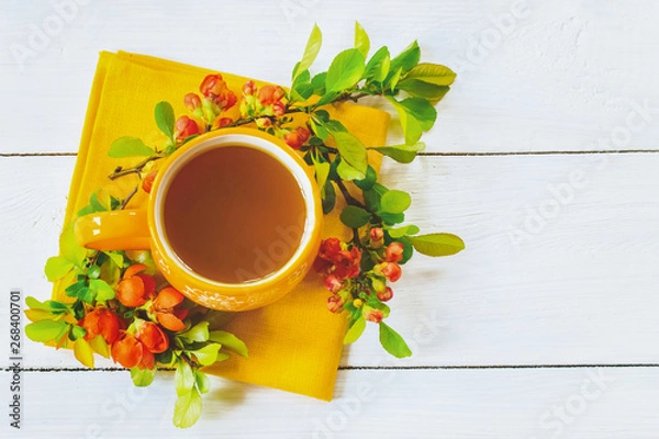 Fototapeta spring gentle background with a cup of green tea and branches of orange flowers top view. copy space.