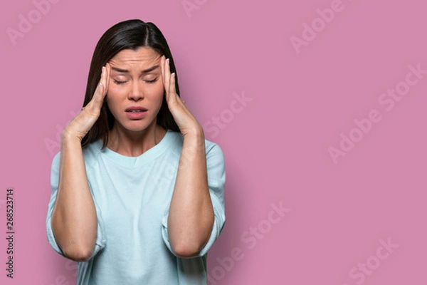 Fototapeta Woman overwhelmed with stress and concern, confusion and doubt, hands to head, on pink background copy space