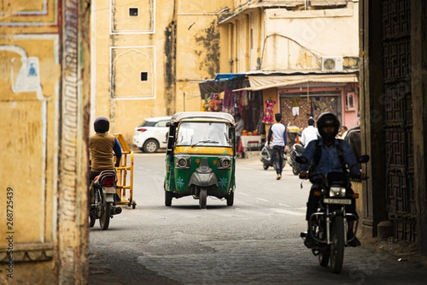 Obraz City life with Auto rickshaw (also known as Tuc Tuc) and motorbikes through the streets of Jaipur. Jaipur is the capital of the Indian state of Rajasthan, India.