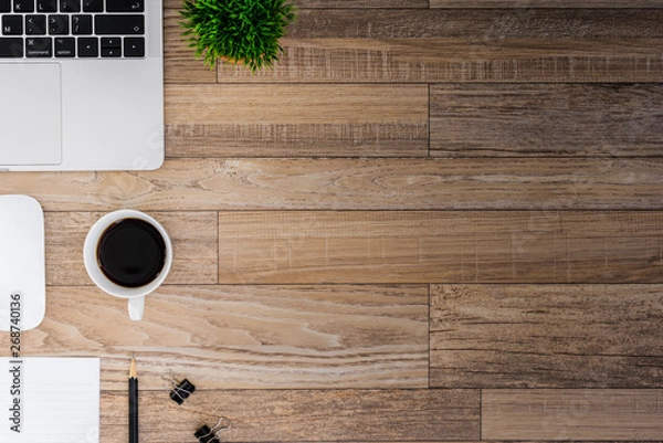 Fototapeta The office desk flat lay view with laptop, mouse, tree, black clip, coffee cup, notebook, pencil on wood texture background.