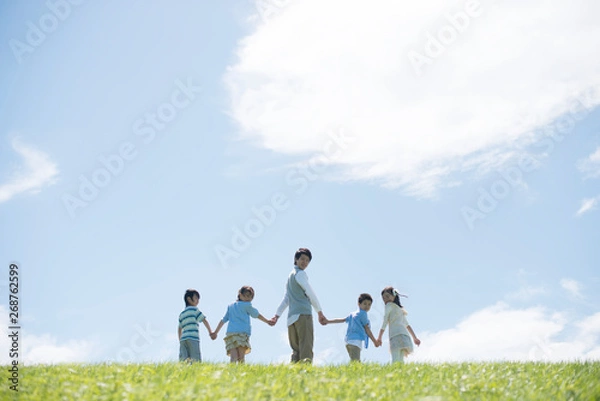 Fototapeta 草原で手をつなぐ小学生と先生