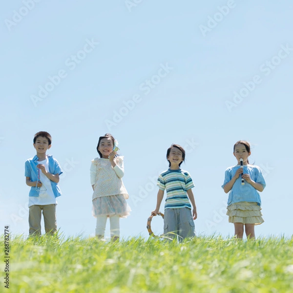 Fototapeta 草原で楽器を持ち微笑む小学生
