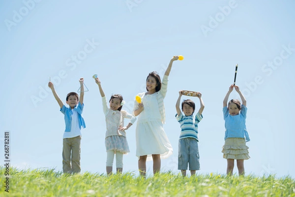 Fototapeta 草原で楽器を持ち微笑む小学生と先生