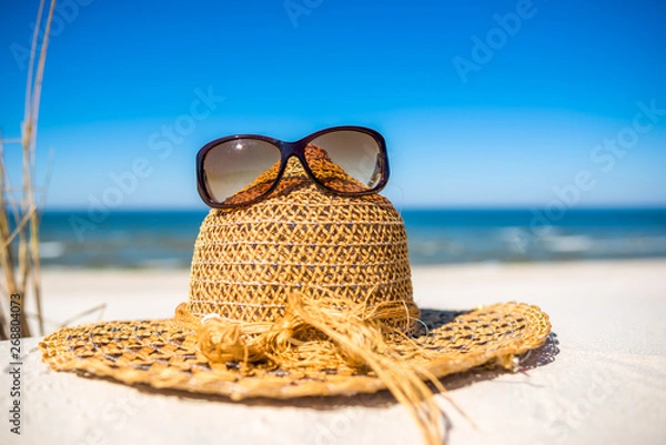 Obraz Summer beach accessories - sun hat and sunglasses on sand. Summer vacation background, Baltic Sea, Poland.