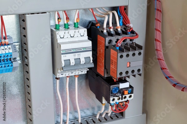 Obraz Circuit breaker, contactor or starter with additional contacts and thermal relay in electrical Cabinet. Electric control Cabinet for pumps or motors. The wires are connected to electrical equipment.