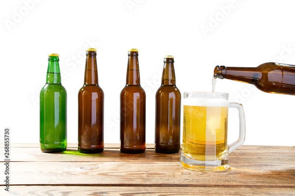 Fototapeta Glass and bottle of beer with no logos on wooden table isolated copy space, bottle mock up. Beer bottle studio shot with cap isolated.