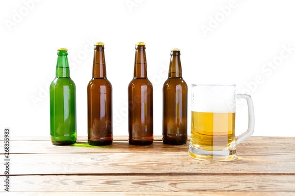 Fototapeta Glass and bottle of beer with no logos on wooden table isolated copy space, bottle mock up. Beer bottle studio shot with cap isolated.