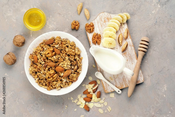 Fototapeta Granola with nuts and milk on a bright table.