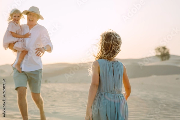 Fototapeta Father with two daughters in the desert in Dubai
