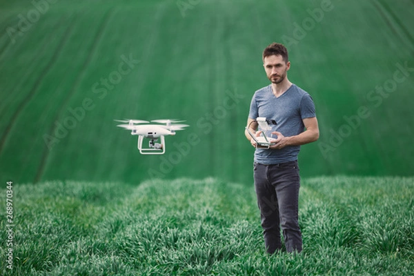 Obraz Young man piloting a drone on a spring field