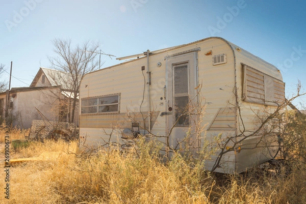 Obraz Retro abandoned travel trailer RV in an overgrown yard