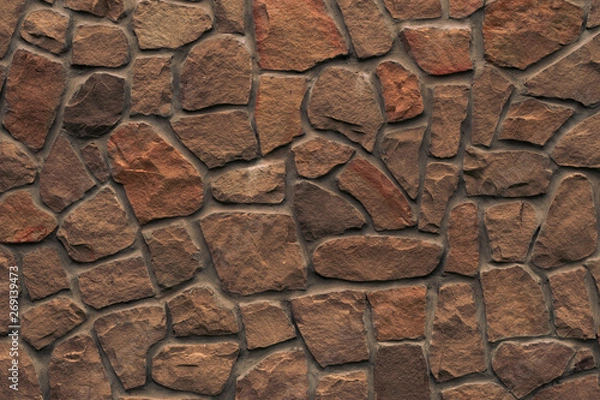 Obraz Orange stone wall. Bright brown rock texture. Red faceted stone wall background for design. Modern architecture, granite structure. Red brick wall grunge background. Cement construction material textu