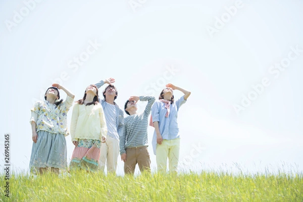 Fototapeta 草原で空を見上げる大学生