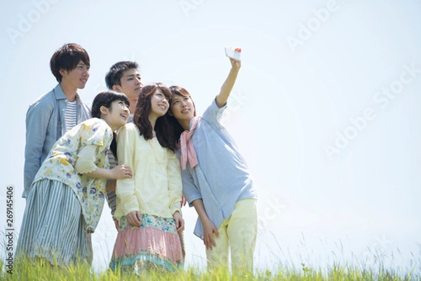 Fototapeta 草原で自分撮りをする大学生