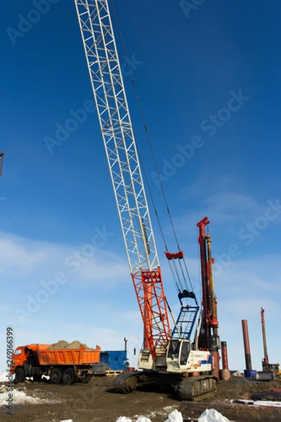 Fototapeta Drilling equipment, excavators, trucks and Construction cranes build the sea port of Sabetta. Yamal, Russia. Winter, sunny