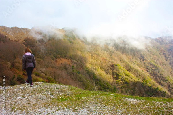 Fototapeta girl walks alone in the mist and fog along the paths of the Apuan Alps in Tuscany
