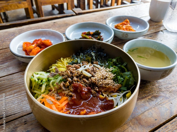 Fototapeta Traditional Korean bibimbap, a dish of rice, meat and vegetables, served in a hot stone bowl, in the town of Jeonju in South Korea