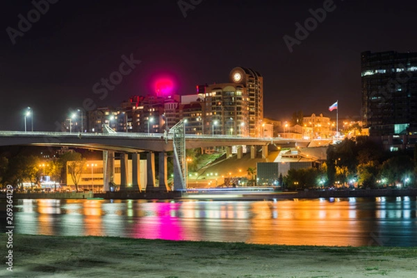 Fototapeta Sandy beach and bridge over the river and night city on the background.