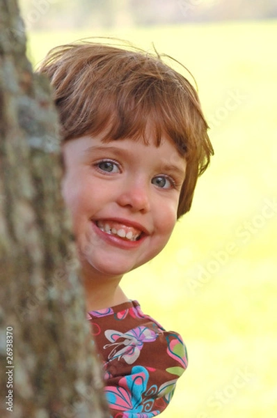 Fototapeta Child peeking from behind a tree