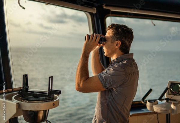 Fototapeta Navigational officer lookout on navigation watch looking through binoculars. Marine industry. COLREG collision regulations