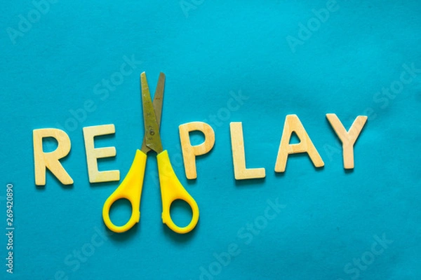 Fototapeta Top view of the word replay and a scissor sitting on a blue background