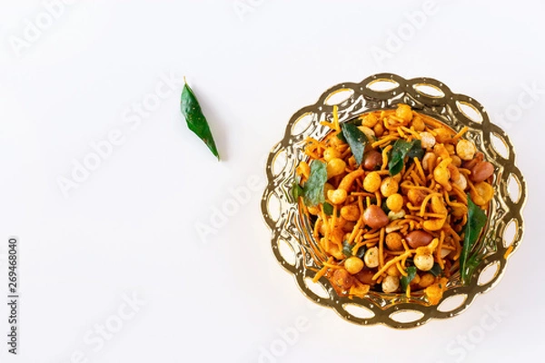 Obraz South indian spicy crunchy mix Nimco or Namkeen with peanut, rice, curry leaves and spice golden bowl background isolated top view.