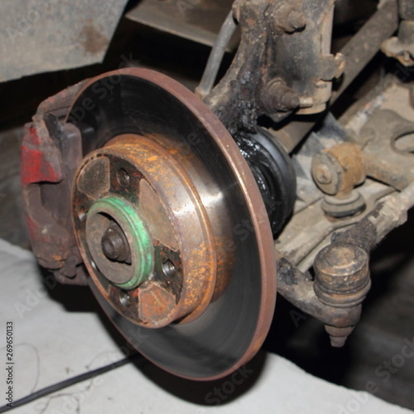 Fototapeta Brake disk and destroyed CV joint duster, hub and sterering rod - repair car suspension and gear drive on left side with removed wheel