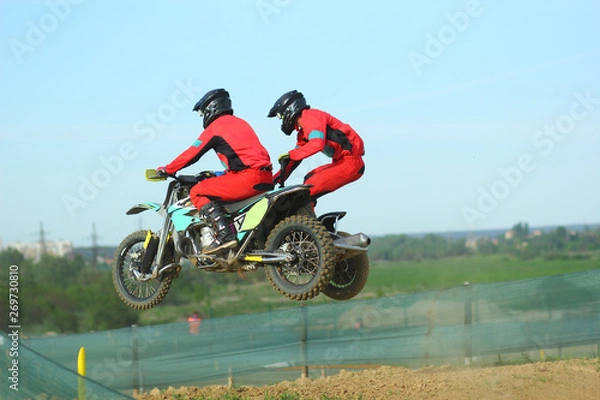Fototapeta Sidecar motocross athletes jumping on the dirt track 
