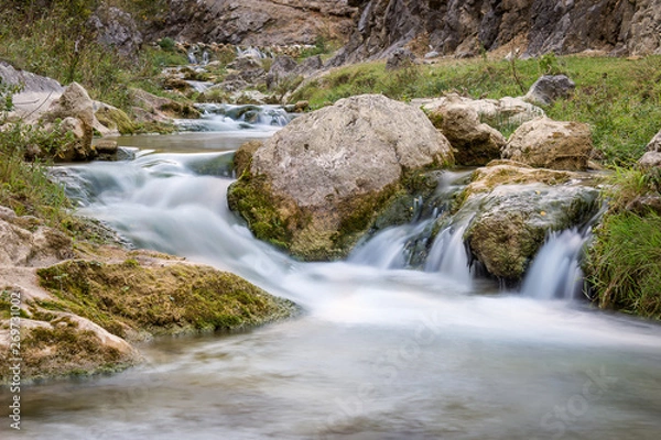 Fototapeta Smooth, silky water of long exposure mountain creek in a canyon, close up