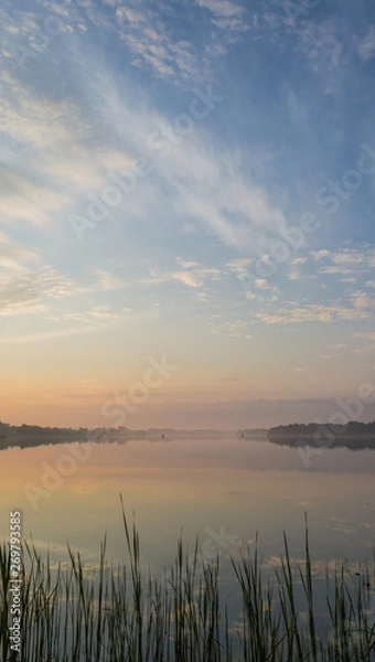 Fototapeta Sunset over the lake. Cloudy sky over calm water surface.