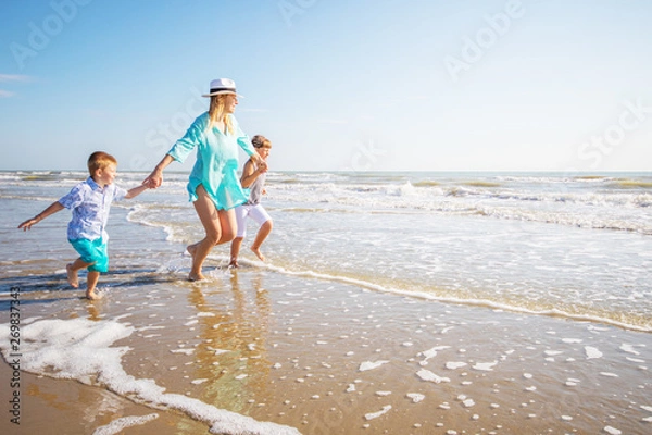 Obraz matka i jej dzieci bawiące się na plaży
