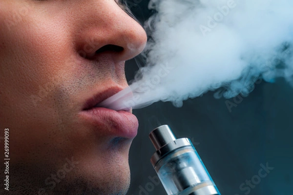 Fototapeta Close-up - young man vaping e-cigarette