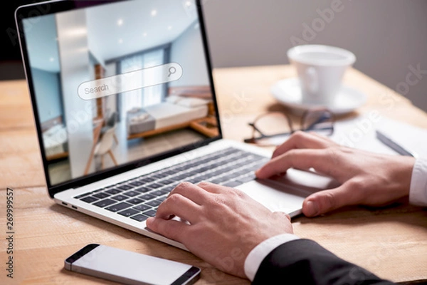 Fototapeta  Buisiness man hand on table using a laptop with hotel room booking