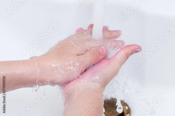 Fototapeta the girl washes away water and soap paint from hands after drawing