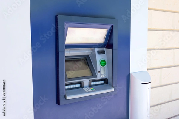 Obraz ATM cash machine in the wall of a building on a city street, operating and functional, no people near.