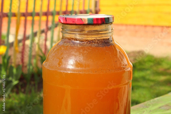 Fototapeta Fresh kvass in a glass jar in the garden. Close-up. Background.