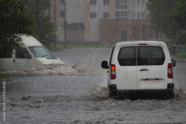 Fototapeta car rides in heavy rain on a flooded road