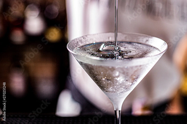 Fototapeta vodka martini isolated on a black background with an olive splashing and air bubbles