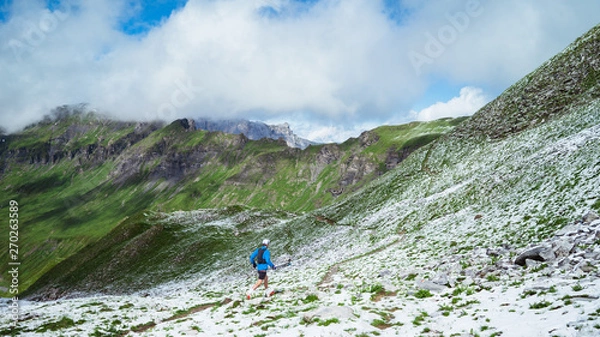 Fototapeta A runner on the snowy trails of the Alps in spring
