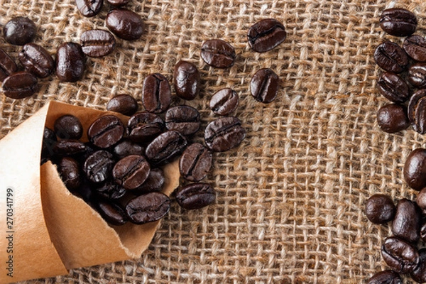 Obraz The coffee grains scattered on a table near a cup with coffee