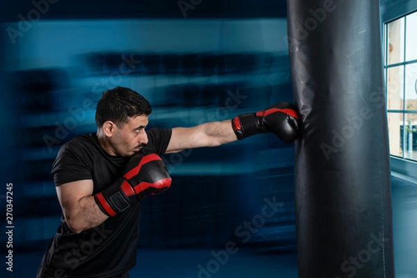 Fototapeta Eastern Arab boxer looks at the box with a punching bag.