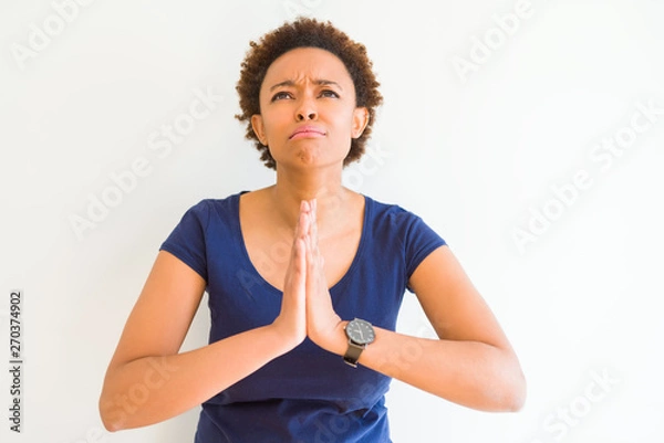 Obraz Young beautiful african american woman over white background begging and praying with hands together with hope expression on face very emotional and worried. Asking for forgiveness. Religion concept.