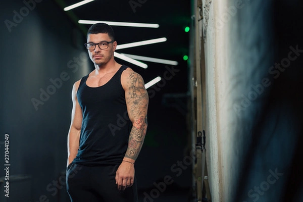 Fototapeta Młody siłacz w siłowni w okularach i podkoszulku