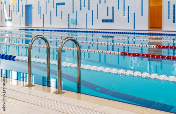 Fototapeta Swimming pool with marked red and white lanes. Empty swimming pool without people with quiet standing water. Water sports in indoor pool.