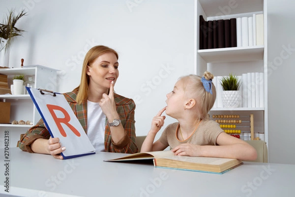 Fototapeta Cute girl with speech therapist in cabinet trainiing pronunciation