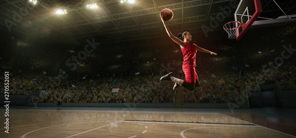 Obraz Female basketball player makes slam dunk. Basketball player on big professional arena during the game