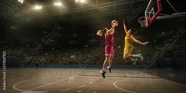 Fototapeta Female basketball players fight for the ball. Basketball player makes slam dunk on big professional arena during the game